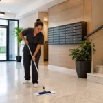 Agent d'entretien professionnel nettoyant le hall d'une copropriété moderne avec du matériel adapté