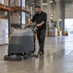 Agent d’entretien utilisant une autolaveuse sur un sol industriel en entrepôt